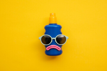 Suncream lotion bottle with a sad face and sunglasses. Summer sunburn concept