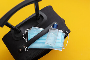 Covid travel concept. Suitcase with a protective face mask and hand sanitiser