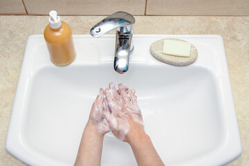 A Hands with soap are washed under the tap with water. Clean from infection and dirt and virus. At...