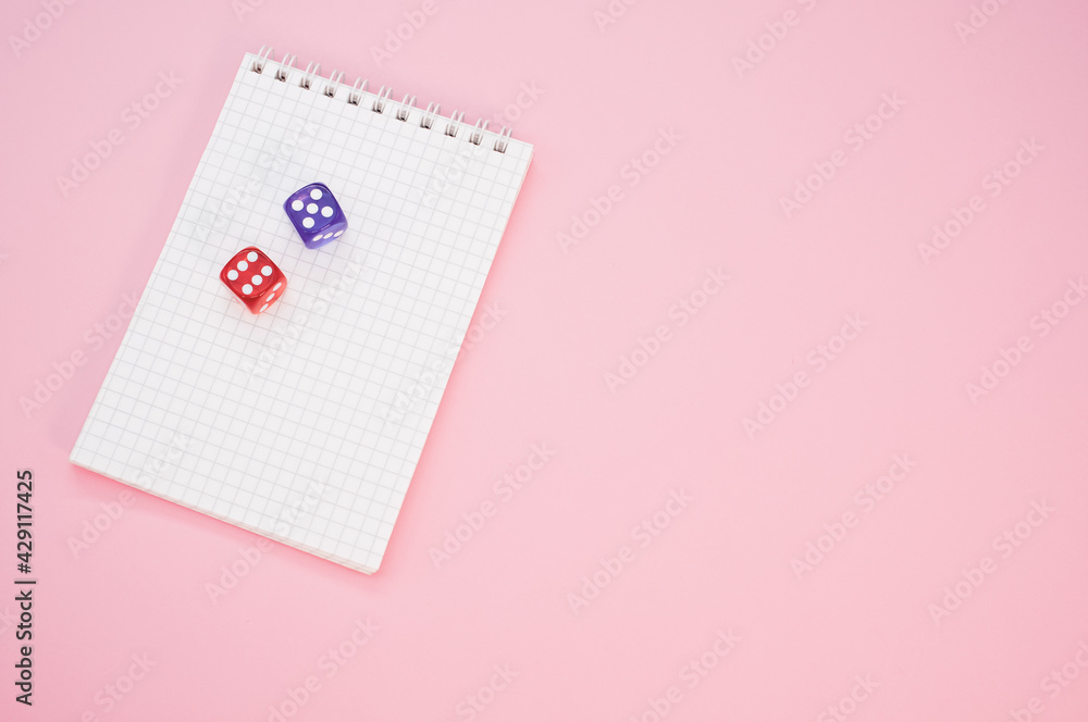 Poster top view of two rolling dices on a notebook isolated on a pink background