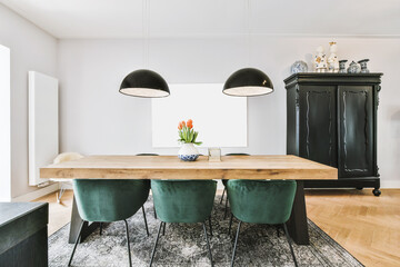 Comfortable chairs and wooden table with flowers placed under stylish lamps against wall with...