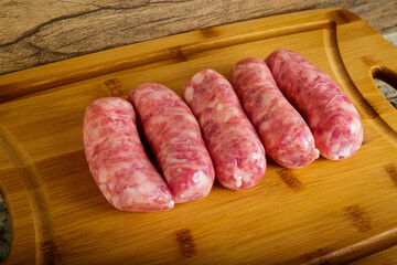 Raw sausages on the wooden board.