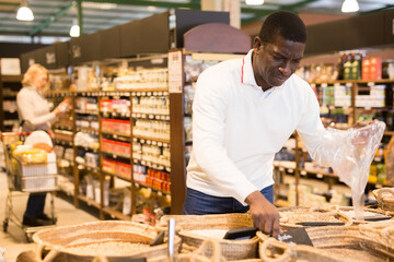 African American man buying natural organic groats in supermarket ..