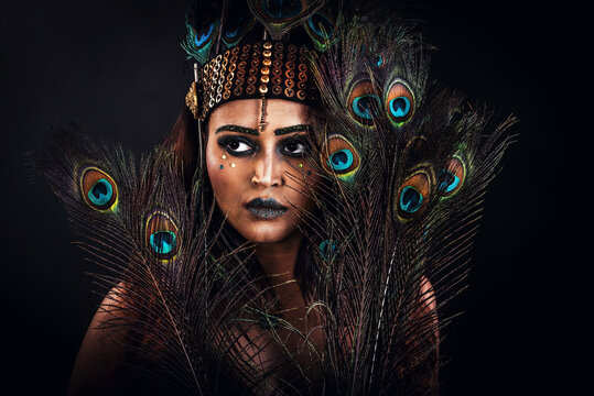 Beautiful woman dressed in a peacock dress poses in the studio