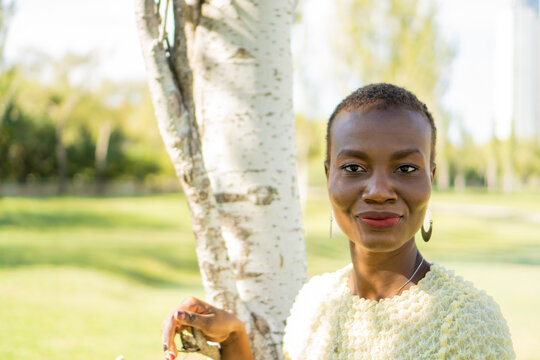Portrait of an African-American woman standing in a park, straight to the camera. horizontal pic