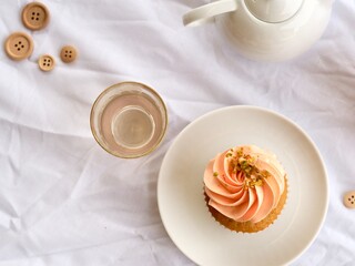 Pretty pink cupcake and pink glass with teapot on a white bright background