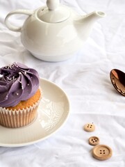 Pretty cupcake with purple icing on a textured white background