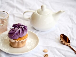 Cupcake and white teapot on a pretty white textured background