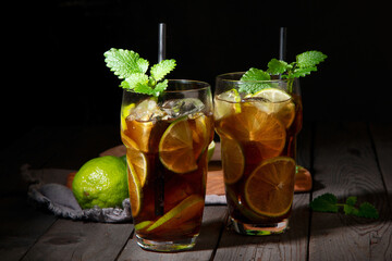 Fresh made longdrink Cuba libre cocktail on dark background.