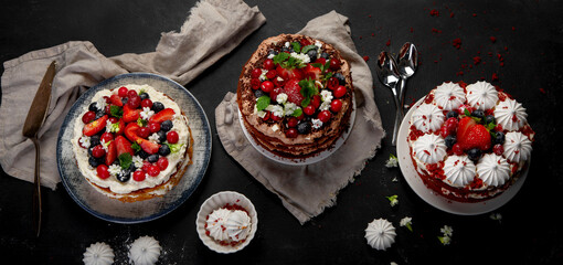 Assorted delicious and colorful homemade cakes with different type of filling on black background.