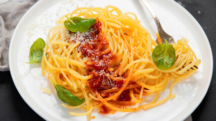 Delicious appetizing Italian pasta spaghetti with tomato sauce, parmesan and basil on a plate on a gray background. Top view, copy space