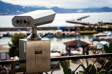 Close-up metal binoculars for public use with views of the beautiful antique city, port and sea
