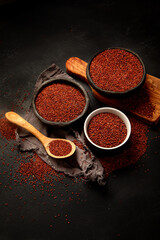 Red quinoa seeds on dark background. Healthy vegan food concept.