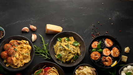Assortment of Italian pasta with traditional sauces for dinner on dark background.