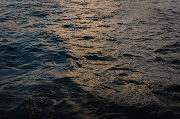 Wave surface of dark blue river with sun light on water when sunset background.