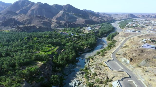 Aerial view of palm fields surrounded by Al Hajar Mountains in Oman