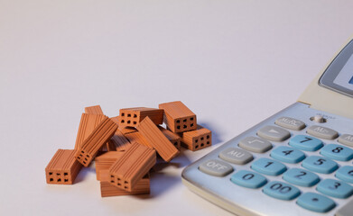 Pile of bricks next to a calculator on a white background. Home loan real estate for mortgage concept
