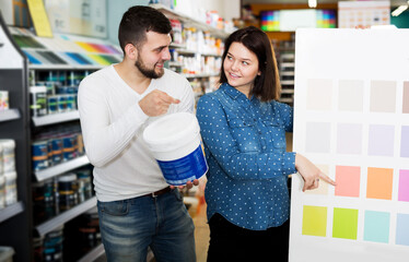 Couple in love examining color scheme variants in paint supplies store