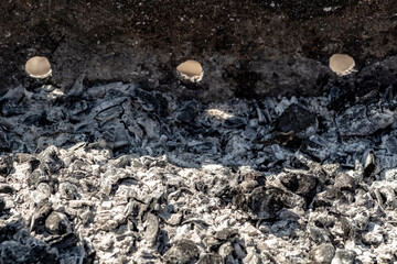 Black burnt coals in the grill close-up.