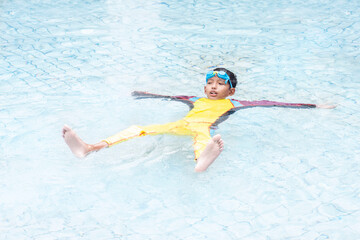 Asian boy wearing a swimsuit that floats in water. It is a practice of survival skills even if you can't swim.