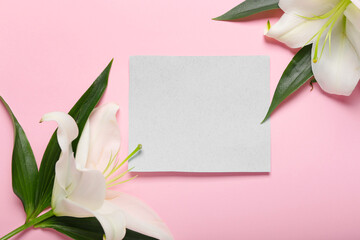 Beautiful lily flowers and blank card on color background, closeup