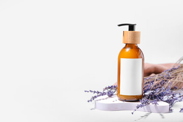 Bottle of natural shampoo and lavender flowers on white background