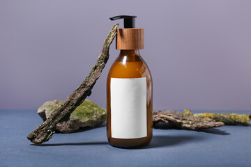 Bottle with natural shampoo and tree bark on color background