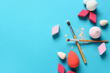 Makeup sponges and brushes on color background