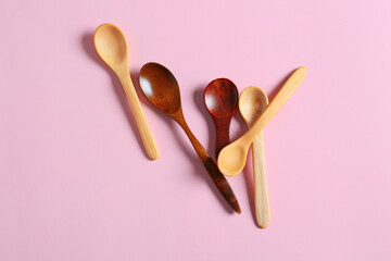 Different wooden spoons on color background