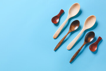 Different wooden spoons on color background