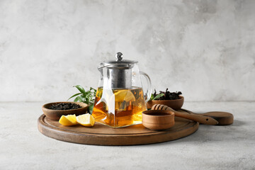 Teapot of tasty black tea with lemon and honey on light background