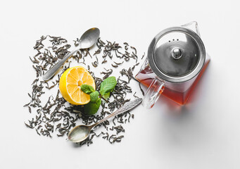 Composition with teapot of tasty black tea and lemon on white background