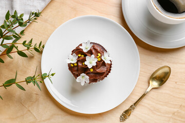 Plate with tasty chocolate cupcake on wooden background