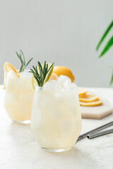 Glasses of cold tea with rosemary and lemon on light background