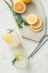 Glasses of cold tea with rosemary and lemon on light background