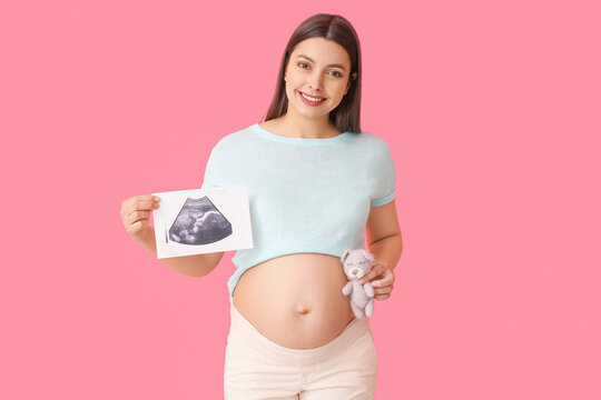 Young pregnant woman with sonogram image and toy on color background