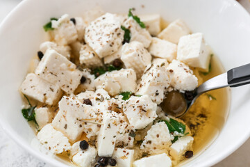 Bowl with tasty feta cheese, oil and spices, closeup
