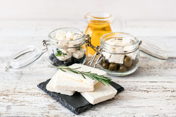 Tasty feta cheese, oil and olives on light wooden background