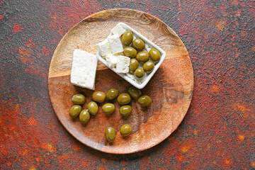 Bowl with tasty feta cheese and olives on grunge background