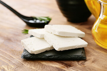 Tasty feta cheese and oil on wooden background, closeup