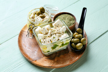 Bowl with tasty feta cheese, oil and olives on color wooden background