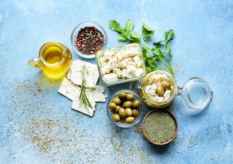 Bowls and jar with tasty feta cheese, oil and olives on color background