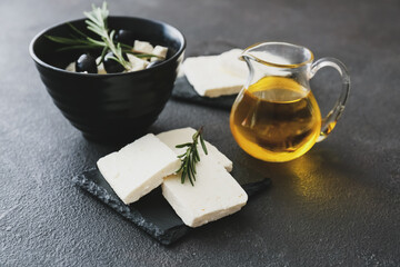Bowl with tasty feta cheese, rosemary and olives on dark background