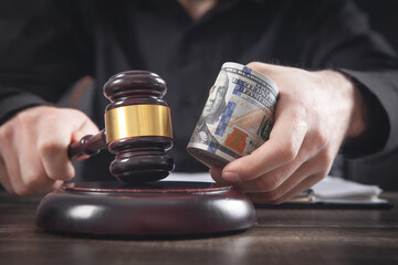 Male judge holding money and judge gavel.