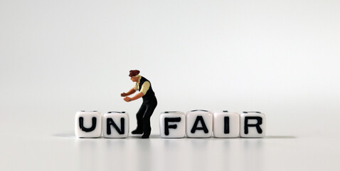 The word UN on white cubes and the word FAIR on white cubes. White cube with words and miniature people.
