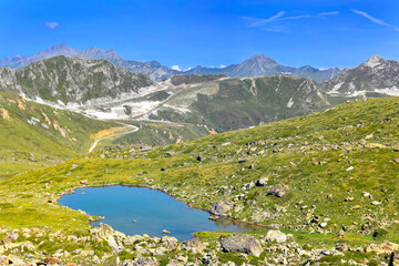 Fototapeta na wymiar alpine mountain landscape with a little lake in rocky meadow