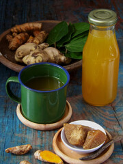 Jamu or Indonesian traditional herbal drink made from turmeric, ginger, betel leaves, tamarind, palm sugar. Healthy drink with mixed sour, sweet, and spicy taste. Ingredients in background