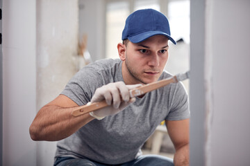 Young adult man painting on a DIY budget renovation of his new home apartment.