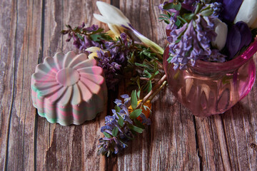Bright organic handmade scented soap in the shape of a flower and spring flowers .