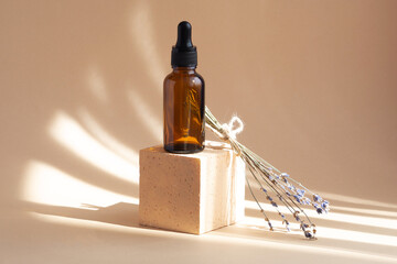 Brown glass bottle with black pipette on beige background with shadows from sunlight on 3d square...